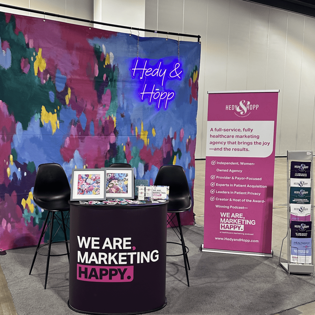 Hedy & Hopp's booth at a conference including a hand-painted backdrop from artist, Jessica Hitchcock.